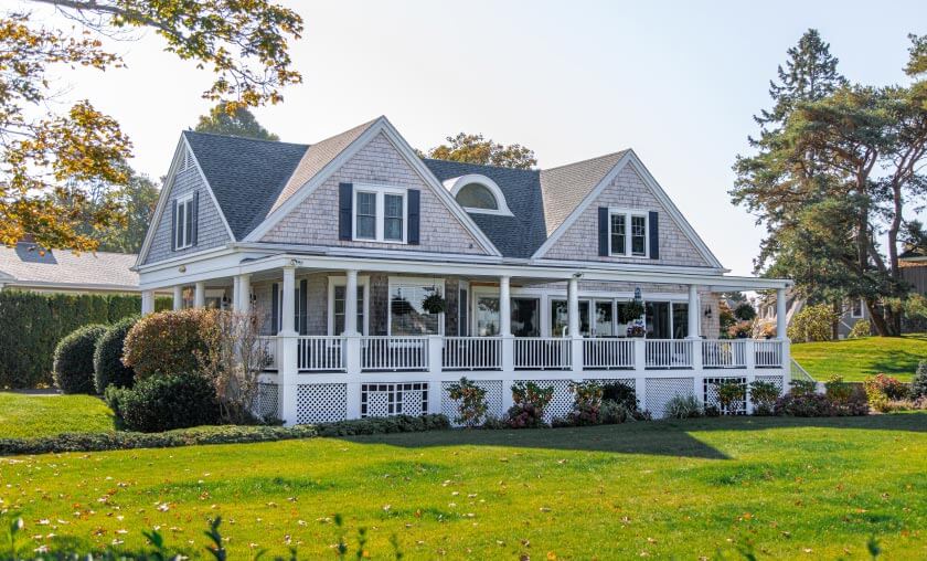 Large suburban home with wraparound porch.