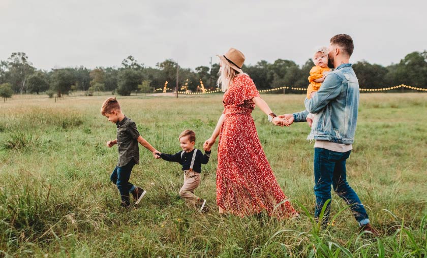 Family walking together through grassy field.