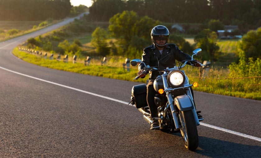 Motorcyclist riding along scenic rural road.