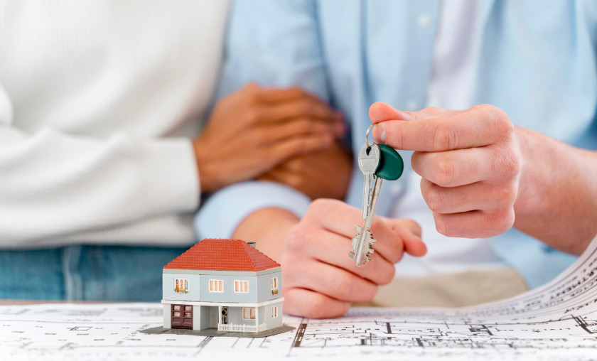 Couple holding house keys over blueprints.